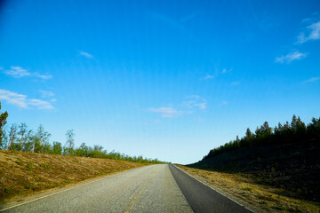 View from car windscreen with stripe relief to highway, tundra and blue sky in norht region at a sunny day