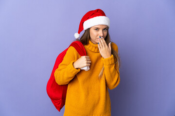 Lithianian woman with christmas hat isolated on purple background happy and smiling covering mouth with hand