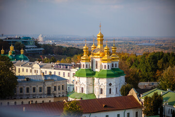 Beautiful yellow and gold domes of the Orthodox Church against the background of the blue sky and the city. Domes of the Assumption Cathedral of the Kiev-Pechersk Lavra.