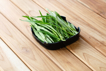 fresh raw morning glory sliced on square plate isolated on wooden background, shabu, hot pot ingredients