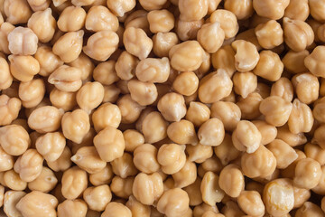 Close-up of a plate full of raw white chickpeas that turn yellow after soaking.
. Organic textures as a background. Vegan food.