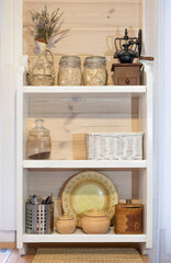 Scandinavian rustic white open wood shelf in the kitchen. With glass jars, jugs and pots
