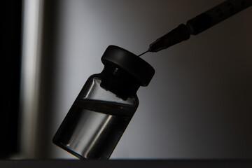 Silhouette of full vaccine vial with a syringe during the Covid-19 coronavirus pandemic outbreak