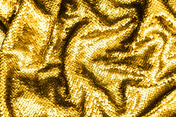 Golden shiny fabric with sequins, abstract background.