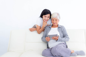 Grandmother learning how to use tablet with her granddaughter. Family bonding and the elderly care concept.