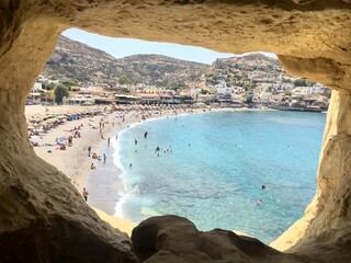 Panorama of Matala beach and caves,Greece, with azure clear water, sandy beach and relaxing people.Calm summer atmosphere.Famous tourist place.Holiday travel concept