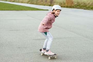 Adorable teenage girl drives with skateboard n helmet