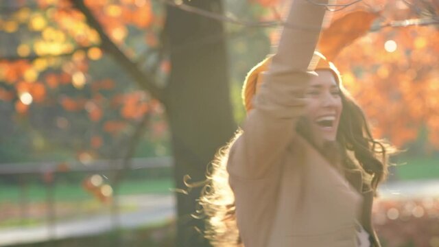 Hello october. smiling middle aged woman in brown coat and yellow hat having fun time outdoors in the city park in autumn. 