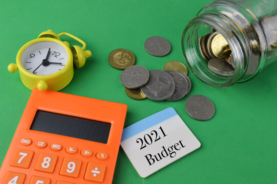 Selective focus of coins, calculator, clock, pen and wooden board written with text CRISIS $ isolated on a green background. 