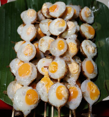 focus on Popular Thai street food,  Fried quail eggs served on a skewer known as khanom krok nok...