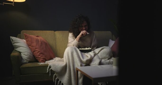 The girl is watching a comedy on TV. To watch series. The girl on the couch with popcorn is watching a movie. 4k slow motion video