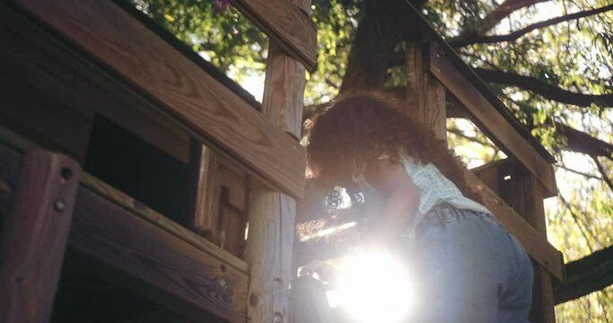 Cute little girl climbing up ladder of a tree house