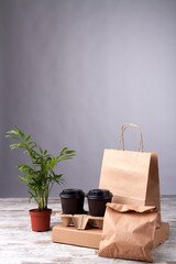 Paper cups and eko packages on wooden floor. Order of food delivery. Flowerpot on the wooden board.