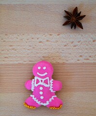 Christmas composition: cookie in the shape of a gingerbread man on a wooden background with a piece of star anise on it