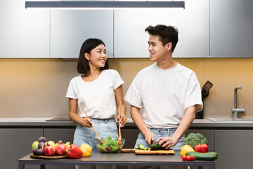 Joyful Korean Couple Cooking Together In Kitchen Preparing Vegetarian Dinner