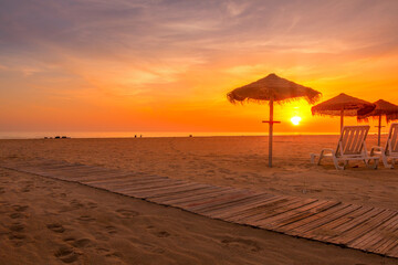 Autumn sunset at the beach with straw beach hats and sun loungers