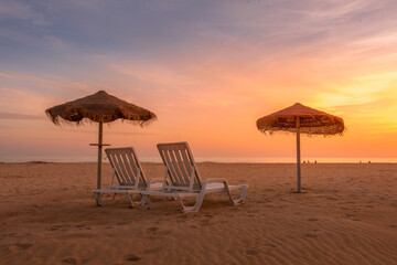 Autumn sunset at the beach with straw beach hats and sun loungers