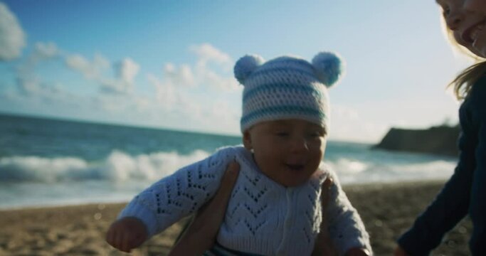 A little preschooler on the beach is hugging his baby brother in the autumn sun