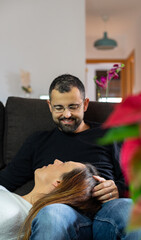 Woman rests her head on the legs of her partner on the couch. Young lovers at home