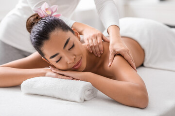 Fototapeta na wymiar Relaxed asian woman enjoying back and shouders massage in spa