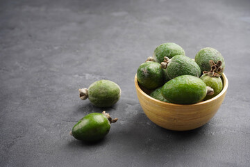 Feijoa in bamboo bowl on gray concrete background. Vitamin, immunity, recipe concept. Close-up, copy space