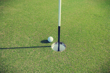 Golfer putting on a perfect golfing green towards the hole