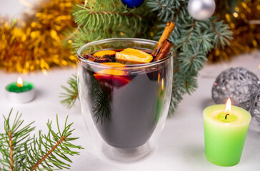 Hot mulled wine with red wine, orange, cinnamon sticks and star anise. Cosy Christmas decoration with candles on white background