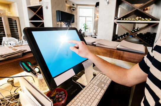 Cropped image of cashier touching computer screen at restaurant counter