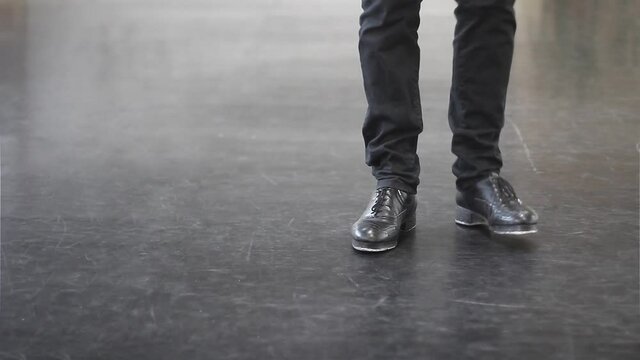 Single male tap dancer wearing black trousers and leather shoes dancing simple irish dance.