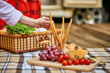 Food lying out on picnic blanket with basket on the background