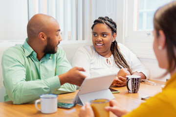 Brazilian business person in informal conversation with teammates at cafe office. Collaboration, creative, discussion, meeting concept..