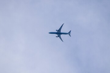 A portrait of a civilian airplane high up in the sky flying by. The belly of the airliner is visible.