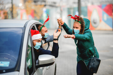 Friends wearing a protective face mask in the car. Holidays during epidemic. 