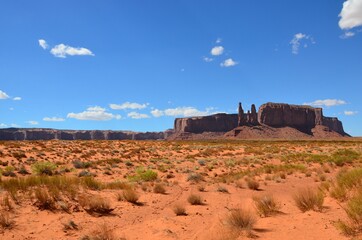 Monument Valley on Utah Arizona border, view towards rock formations called Three Sisters, blue sky, sunny, desert landscape