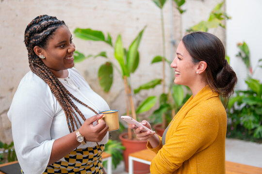 Brazilian business woman talking causally with co-workers outside in the garden. Candid, connection, break, relaxation, chatting concept..