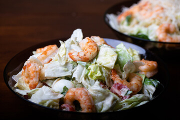 Caesar salad with prawns on a dark background