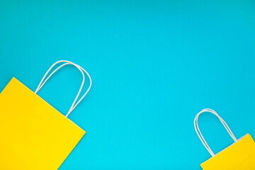 Yellow shopping bags over the blue background. Colorful flat lay with space for text.