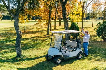 Golf cart on the course with golfer reaching for a golf club in a bag