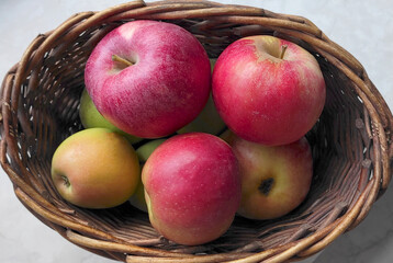 Fresh red apples in a wicker basket on the table