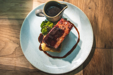 Roasted pork shoulder on dauphinoise potatoes drizzled with gravy and served with a side of brocolli.