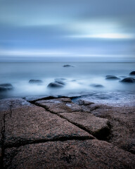 Rocky beach in Emäsalo Finland on a gloomy day next to ocean seaside view with cold feel and long-exposure waves and many rocks and boulders