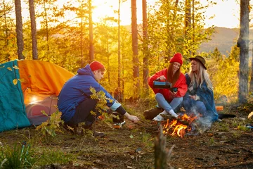 Foto op Plexiglas camping tent camp in nature happy caucasian friends in autumn at nature forest, hike concept. active spending time in mountains, picnic near the bonfire © Roman