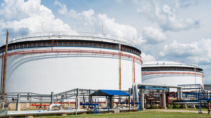 Oil depot storage tanks. Large white Industrial tanks for petrol and oil on dramatic sky background. Petrochemical concept.