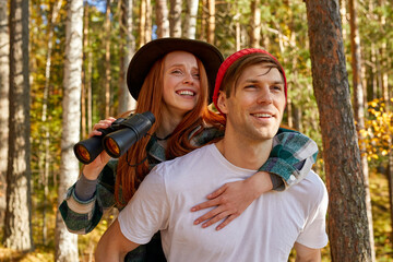 happy caucasian couple having fun during hike, travel in the forest, on mountains. carefree travellers enjoy the nature, use binoculars, smile