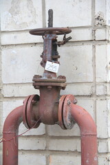 Old damaged and rusty iron oil pipe valve wheel. Metal, pipeline and mechanic concept. An old iron valve on a gas pipe. A valve to cover the pipe with a round handle