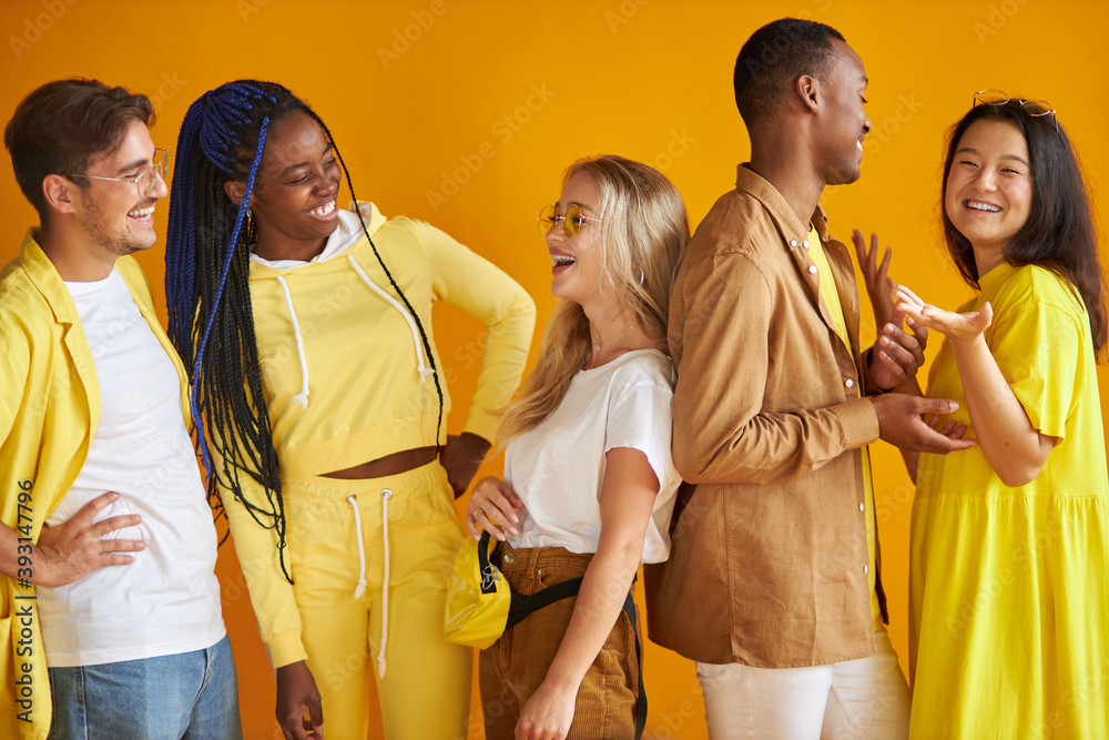 Wall mural cheerful positive group of young people of diverse nationalities posing at camera togeher, wearing f