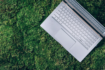Laptop on green grass, moss background. Ecology travel, work outside office concept. Mindfulness,...