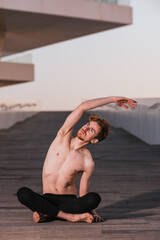 Guru yoga sitting in the lotus position turning his naked torso to stretch.