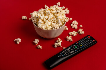 Bowl with popcorn, TV remote and space for text on color background, top view. Watching movie