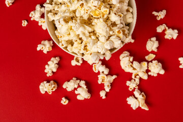A bowl of popcorn on a red background, photo taken from above.